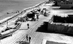 an old black and white photo of people on the beach with boats in the water