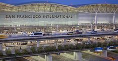 the san francisco international airport terminal is lit up at night, with cars parked in front