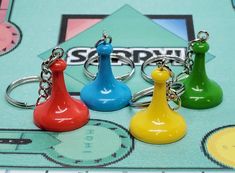 four different colored plastic chess pieces sitting on top of a game board with keychains