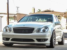 a white mercedes benz parked in front of a house with no one on the street