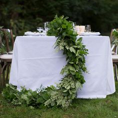 the table is set with white linens and greenery