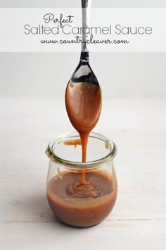 a spoon is pouring caramel sauce into a glass jar on a white surface with the words salted caramel sauce in it