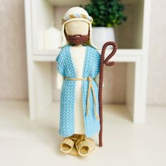 a crocheted figurine holding a cane in front of a white shelf