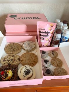 an open pink box filled with cookies and doughnuts on top of a table