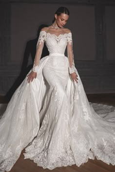 a woman in a wedding dress standing on a wooden floor