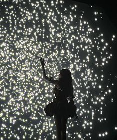 a woman standing on top of a stage with her arms in the air and lights behind her