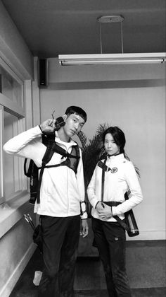 black and white photograph of two people standing next to each other with backpacks on