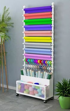 a white rack with lots of different colored pens and markers on it next to a potted plant