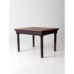 an old wooden table sitting on top of a white floor with no one around it