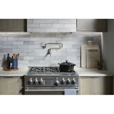 a stove top oven sitting inside of a kitchen next to a counter with utensils on it