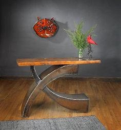 a wooden table sitting on top of a hard wood floor next to a vase filled with flowers