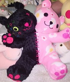 several stuffed animals are lined up together on the floor, one is pink and the other is black