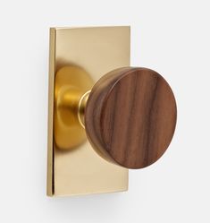 a wooden door knob on a brass plated wall mounted robe hook with an oval wood handle