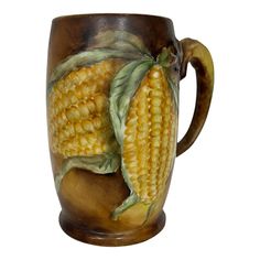 a ceramic mug with two ears of corn on the cob painted on it's side