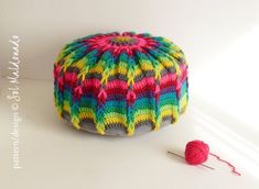 a crocheted poufle with yarn next to it on a white surface