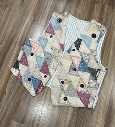 two quilted vests sitting on top of a wooden floor next to each other