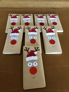 some brown paper bags with santa hats and reindeer noses on them sitting on a table