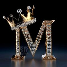 the letter m is made up of gold and crystal stones with a crown on top