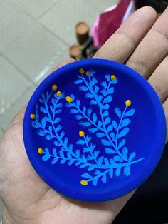 a person holding a blue frisbee with yellow dots on it's rim