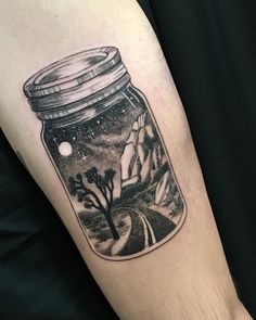 a man's arm with a jar full of water and trees in it on top of him