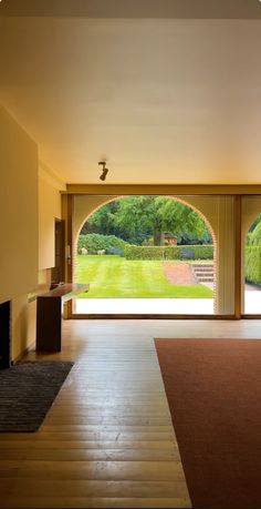 an empty living room with sliding glass doors leading to a large yard and trees in the distance