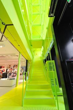 the stairs are painted bright green in this retail store lobby, which is lit up with neon lights