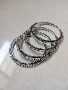 Elegant and ethnic, this Silver Oxidised Bangle set of four is perfect for pairing with traditional attire. Made of mixed metal, they have silver oxidised plating. A great gift idea for your lovely woman or for your beautiful stack of jewelry. Details: Mixed Metal Silver Oxidised Bangles Ethnic Bangles Handmade **Do not use perfumes, sanitizers, or alcohol on or around the jewelry, otherwise it will tarnish. Oxidised Silver Bracelet, Silver Bangles Indian, Oxidised Bangles, Oxidised Jewelry, Bangles Set, The Bangles, Jewelry Details, Mixed Metal Jewelry, Bangles Indian