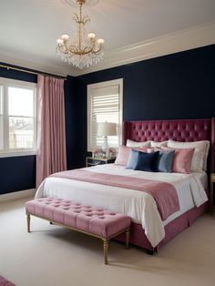 a bedroom with blue walls, pink bedding and a chandelier hanging from the ceiling