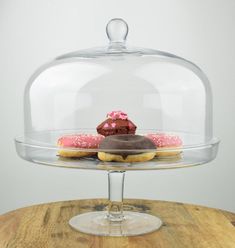 a cake under a glass dome on top of a wooden table