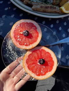 two grapefruit halves are being sprinkled with sugar by someone holding a knife