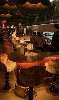 an empty restaurant with many chairs and lights hanging from the ceiling over it's bar