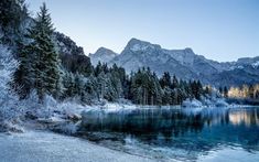 a lake surrounded by snow covered trees and mountains