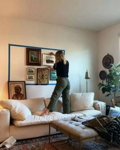 a woman standing on top of a white couch in a living room