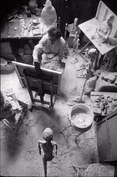 an old black and white photo of people working in a room full of toys, including figurines