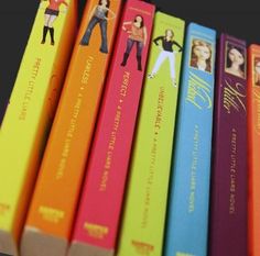 a row of books sitting on top of each other in front of a black background