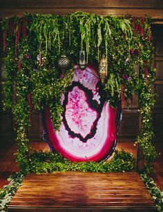 a large piece of art sitting on top of a wooden bench covered in greenery