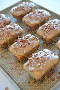 there are many cupcakes with frosting and pecans on the cooling rack