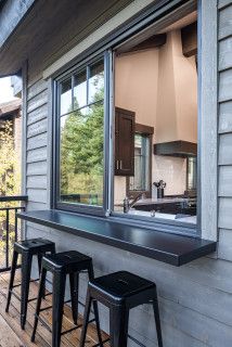 three stools sit on the porch next to an open window and bar with black barstools