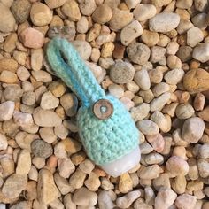 a blue knitted object laying on top of some rocks and gravel with stones around it