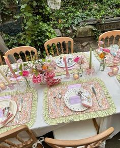 the table is set with pink flowers and place settings for four people to sit at