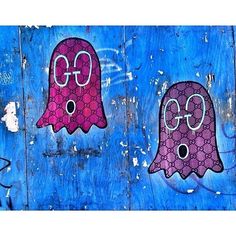 two pink and purple ghost stickers are on a blue wooden wall, one has the word go written on it