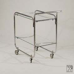 a chrome and glass serving cart with wheels on the bottom, viewed from the front