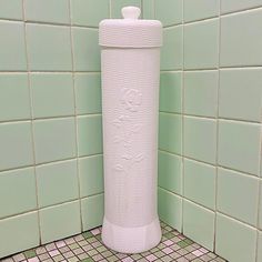 a white urinal sitting on top of a tiled floor next to a green wall