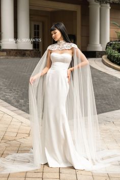 a woman in a white wedding dress with a long veil on her head is posing for the camera