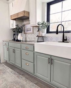 a kitchen with gray cabinets and white counter tops, black faucet above the sink