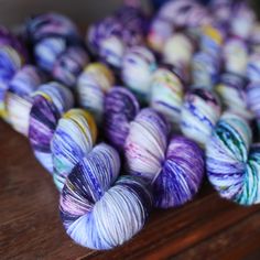 several skeins of yarn sitting on top of a wooden table next to each other