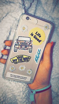 a woman's hand holding an iphone case with stickers on it