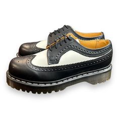 Add A Touch Of Sophistication To Your Casual Look With These Dr. Martens Black White Smooth Leather Wingtip Bex Chunky Oxfords. Made For Men, These Shoes Are Size 7 And Feature A Comfortable Loafer Style. The Black Color Of The Leather Upper Material Complements The White Smooth Wingtip Design And Chunky Sole. The Brand Is Well Known For Its Quality Products And This Pair Of Shoes Is No Exception. Perfect For Any Casual Occasion, These Shoes Are A Must-Have For Any Fashion-Conscious Man. Retro Black Oxfords With Round Toe, Retro Black Round Toe Oxfords, Retro Black Oxfords With Leather Sole, Retro Black Wingtip Oxfords, Black Leather Retro Oxfords, Retro Black Oxfords For Derby, Chunky Sole Shoes, Chunky Oxfords, White Dr Martens