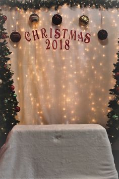 a christmas display with lights and ornaments on it's wall, next to a table