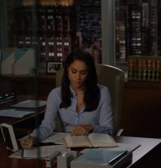 a woman sitting at a desk with an open book